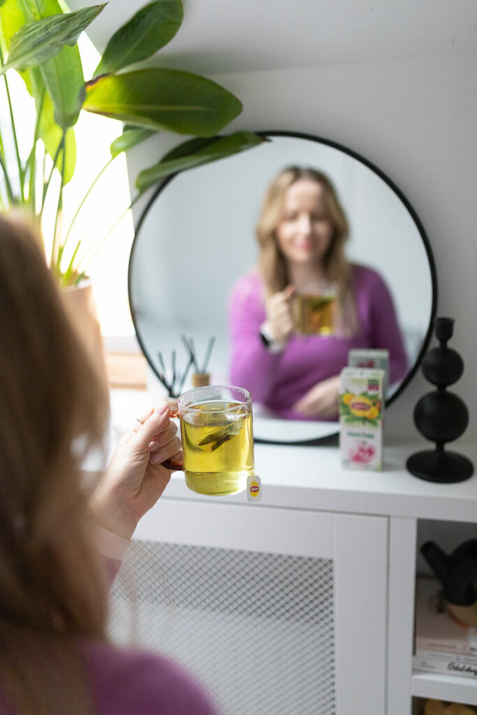 kobieta pije herbatkę przed lustrem