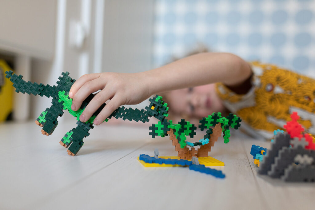 chłopiec bawi się dinozaurem z klocków plus-plus