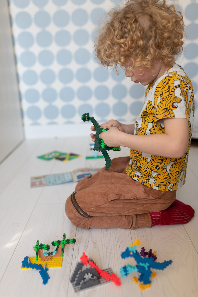 chłopiec bawi się dinozaurem z klocków