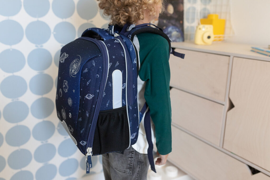 chłopiec pokazuje tył plecaka do pierwszej klasy