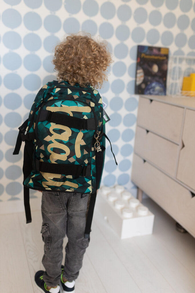 chłopiec pokazuje tył plecaka do szkoły